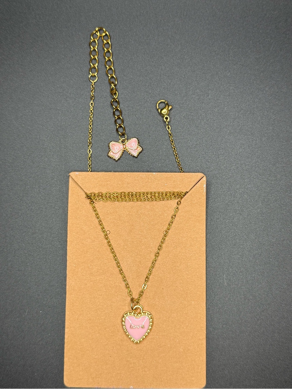 Gold-Tone Necklace with Pink Heart Pendant and bow at the end.